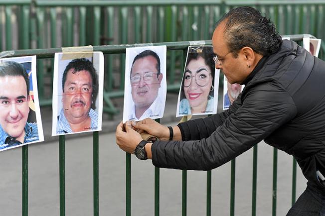 Um membro da imprensa pendura fotos de colegas durante um protesto contra o assassinato ou desaparecimento de jornalistas no México em frente ao Palácio Nacional na Cidade do México em 1º de junho de 2018. O cinegrafista mexicano Javier Enrique Rodríguez Valladares foi morto em Cancun, no sul do país, no estado de Quintana Roo, em 29 de agosto. (AFP/Yuri Cortez)