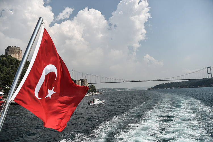 A Turkish flag waves over the Bosphorus strait as Fatih Sultan Mehmet Bridge is seen in the background, on July 22, 2018, in Istanbul. (AFP/Ozan Kose)