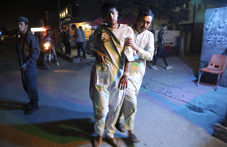 An injured boy is held up outside a hospital following a deadly double bombing attack in Kabul, Afghanistan, on September 5, 2018. Two TOLO News journalists, Samim Faramarz and Ramiz Ahmadi, were killed in the second bombing. (AP Photo/Rahmat Gul)