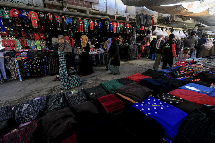 Shoppers walk on a market street in the northeastern Syrian town of Qamishli on May 2, 2018. A prominent Syrian writer was arrested and held for five days in the town in late September and early October 2018. (AFP/Delil Souleiman)