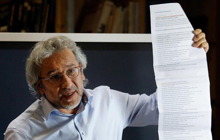 Exiled journalist Can Dündar holds up a list of journalists jailed in Turkey, during a September 28 press conference in Berlin. Prosecutors have asked for Interpol to issue a warrant for Dündar's arrest. (AFP/David Gannon)