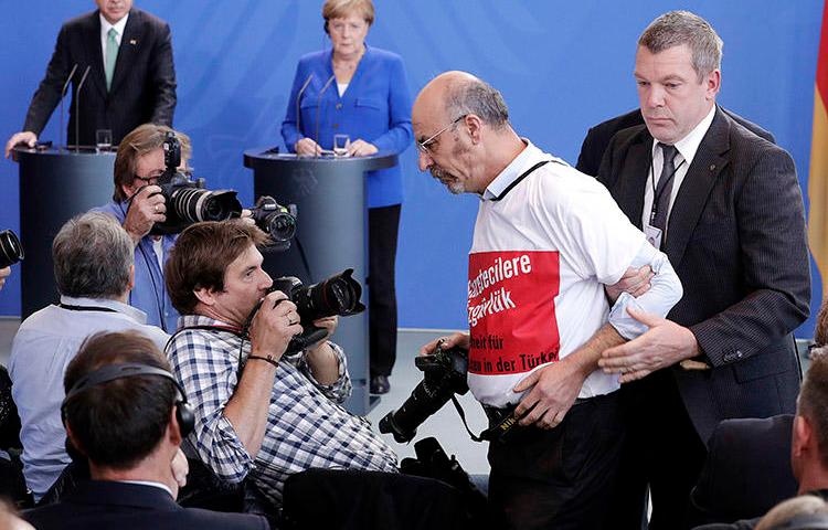 A Turkish man in a 'freedom for journalists' T-shirt is thrown out of a press conference for Turkey's President Recep Tayyip Erdoğan and German Chancellor Angela Merkel in Berlin on September 28. (AP/Michael Sohn)