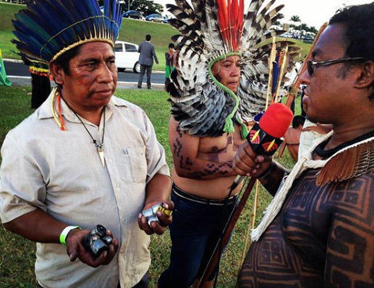 Um membro da Rádio Yandê fala com manifestantes enquanto seguram cápsulas de gás lacrimogêneo durante um protesto, em 2017. (Daiara Tukano)