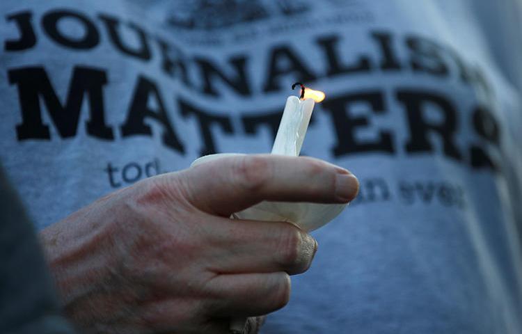 A member of the Capital Gazette takes part in a candlelight vigil near the newspaper's office on June 29. Several local newsrooms are reassessing security after the deadly attack. (Reuters/Leah Millis)