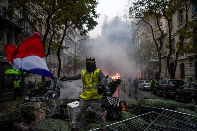 A protester waves the French flag during a rally in Paris on December 1 against a proposed fuel tax hike. Journalists covering the unrest across France and Belgium are at risk of being attacked and injured. (AFP/Alain Jocard)