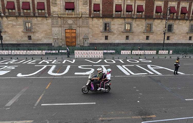 Um policial monta guarda depois que membros da imprensa escreveram mensagens na rua durante um protesto contra o assassinato ou desaparecimento de mais de 140 jornalistas no México desde 2000, em frente ao Palácio Nacional na Cidade do México em 1º de junho de 2018. O corpo do jornalista Alejandro Márquez Jiménez foi encontrado em 1º de dezembro de 2018, perto de Tepic, capital do estado de Nayarit, no noroeste do país. (AFP/Yuri Cortez)