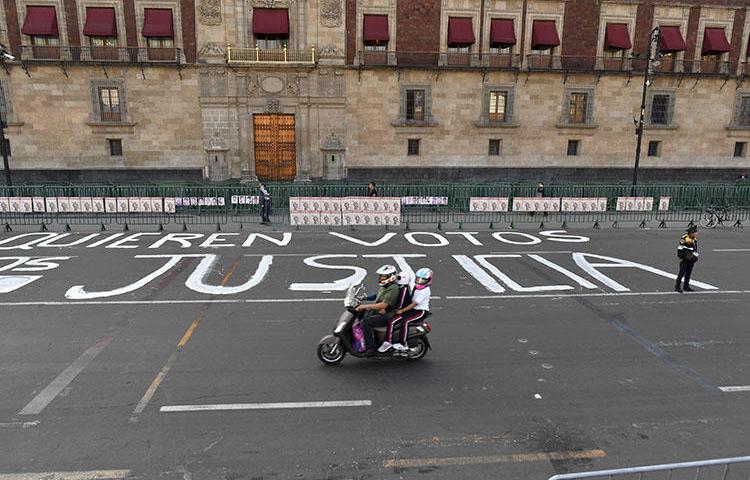 Un oficial de policía hace guardia después de que miembros de la prensa escribieron mensajes en la calle durante una protesta contra el asesinato o la desaparición de más de 140 periodistas en México desde el 2000, frente al Palacio Nacional en la Ciudad de México el 1 de junio de 2018. El cuerpo El periodista Alejandro Márquez Jiménez fue encontrado el 1 de diciembre de 2018, cerca de Tepic, la capital del estado noroccidental de Nayarit. (AFP/Yuri Cortez)