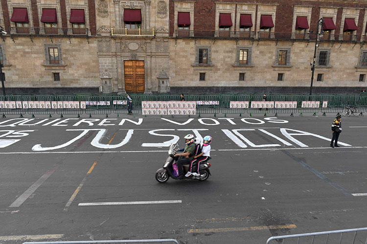 Un oficial de policía hace guardia después de que miembros de la prensa escribieron mensajes en la calle durante una protesta contra el asesinato o la desaparición de más de 140 periodistas en México desde el 2000, frente al Palacio Nacional en la Ciudad de México el 1 de junio de 2018. El cuerpo El periodista Alejandro Márquez Jiménez fue encontrado el 1 de diciembre de 2018, cerca de Tepic, la capital del estado noroccidental de Nayarit. (AFP/Yuri Cortez)