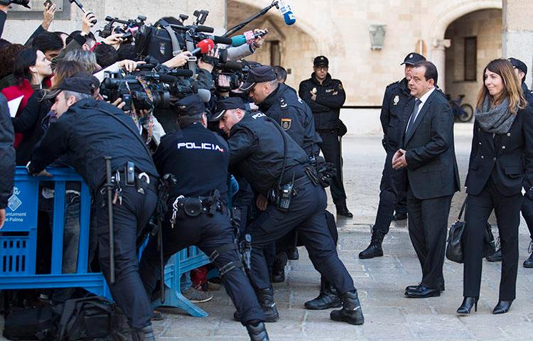 Agentes policiales se ubican entre periodistas y la procuradora pública española en las afueras de los tribunales de Palma de Mallorca, en la isla de Mallorca en febrero 2017. En diciembre 2018, agentes policiales confiscaron equipos y documentos de dos agencias de noticias en conexión con una investigación sobre información filtrada. (Jaime Reina/AFP)