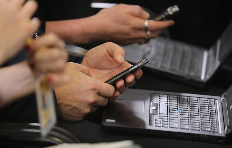 Jornalistas trabalham em seus telefones e laptops durante uma coletiva de imprensa em Bruxelas, em dezembro. Os hackers estão usando métodos sofisticados de phishing para tentar acessar as contas de repórteres e defensores dos direitos humanos (AFP/Ludovic Marin)