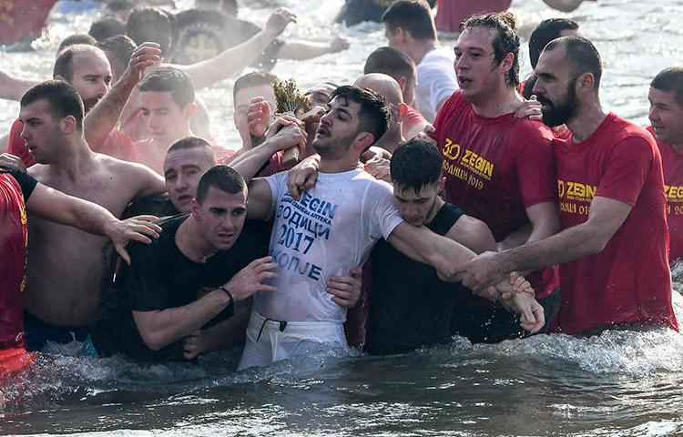 Participants in a religious event pull a cross out of the river Vardar in Skopje during Epiphany on January 19. A journalist covering the event says a security guard attacked her when she tried to interview one of the people taking part. (AFP/Robert Atanasovski)
