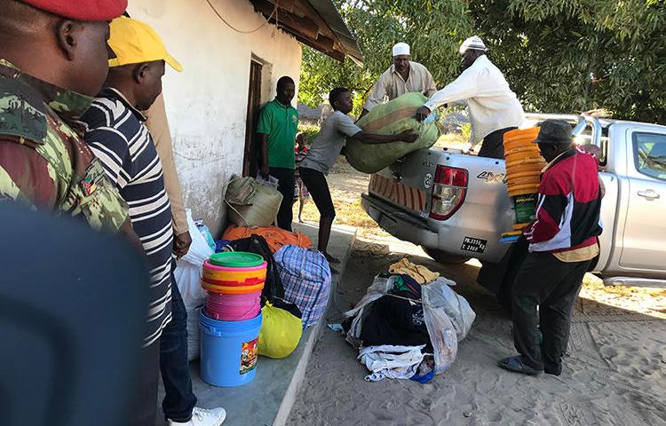 Deslocados internos descarregam comida, cobertores e outros bens depois de fugirem dos ataques de combatentes em Naunde, no norte de Moçambique, em 13 de junho de 2018. Um jornalista moçambicano foi detido em 5 de janeiro de 2019 e mantido numa prisão militar depois de fotografar famílias que fugiram de ataques de militantes. (AFP/Joaquim Nhamirre)