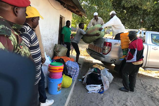 Deslocados internos descarregam comida, cobertores e outros bens depois de fugirem dos ataques de combatentes em Naunde, no norte de Moçambique, em 13 de junho de 2018. Um jornalista moçambicano foi detido em 5 de janeiro de 2019 e mantido numa prisão militar depois de fotografar famílias que fugiram de ataques de militantes. (AFP/Joaquim Nhamirre)