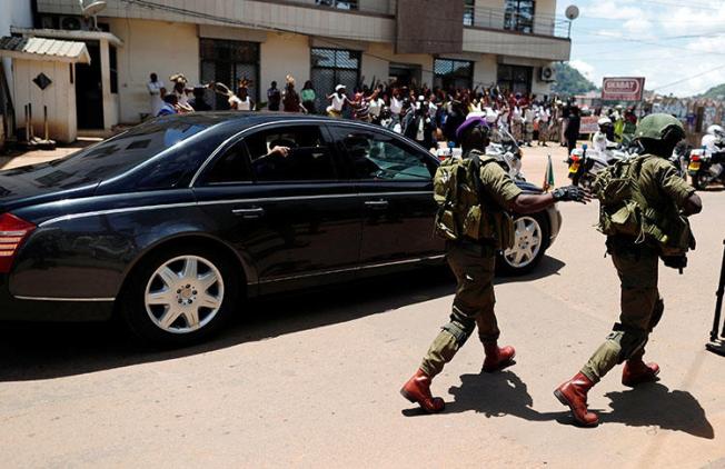 A security guard walks beside the car of Cameroonian President Paul Biya after casting his ballot in the presidential election in Yaounde, Cameroon, on October 7, 2018. Two Cameroonian journalists were detained while covering an opposition gathering in Douala on January 28, 2019. (Reuters/Zohra Bensemra)