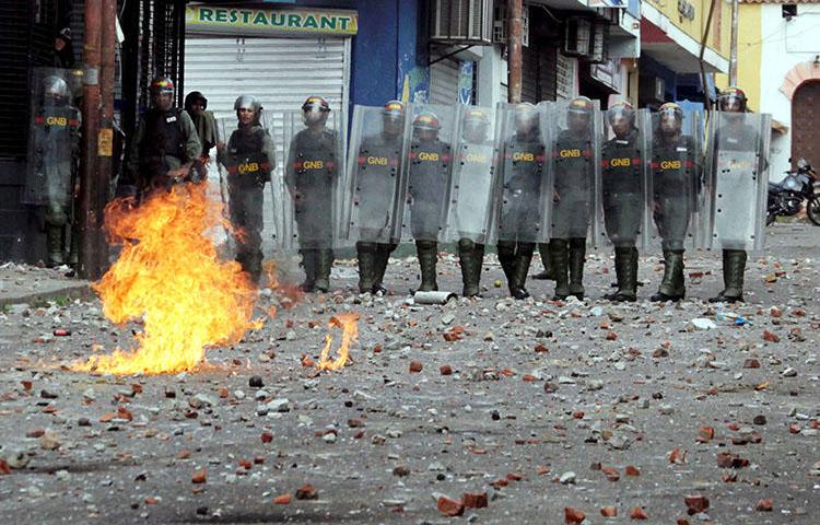 Security forces look on during clashes at a rally in Venezuela on January 24. Amid the political crisis and widespread protests, Venezuelan authorities have raided news outlets, detained journalists and confiscated equipment. (Reuters/Carlos Eduardo Ramirez)