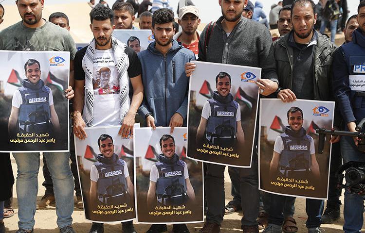 Palestinians hold portraits of reporter Yasser Murtaja on April 13, 2018. A UN commission recently stated that Murtaja and fellow Palestinian journalist Ahmed Abu Hussein were 'intentionally shot' by Israeli snipers. (Thomas Coex/AFP)