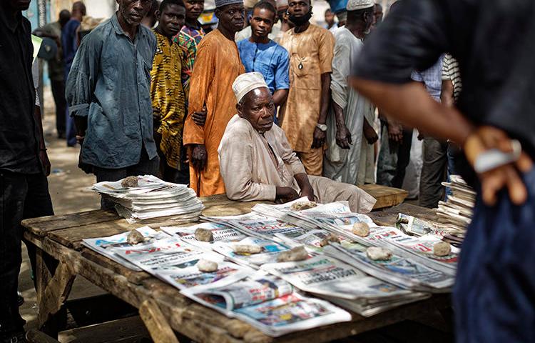 People gather around a newspaper stand in Kano, northern Nigeria, on February 24, 2019. Journalist Obinna Don Norman was recently charged under Nigeria's 2015 cybercrime act. (Ben Curtis/AP)