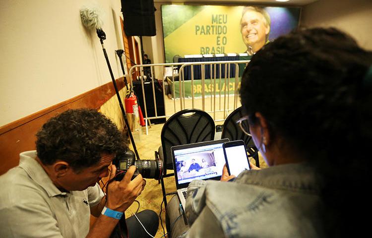 Jornalistas acompanham o Facebook Live de Jair Bolsonaro, legislador de extrema direita e candidato presidencial do Partido Social Liberal (PSL), no Rio de Janeiro, Brasil, em 7 de outubro de 2018. Depois de assumir o cargo em janeiro, Bolsonaro e seus partidários tornaram o trabalho dos jornalistas brasileiros mais difícil. (Reuters/Sergio Moraes)