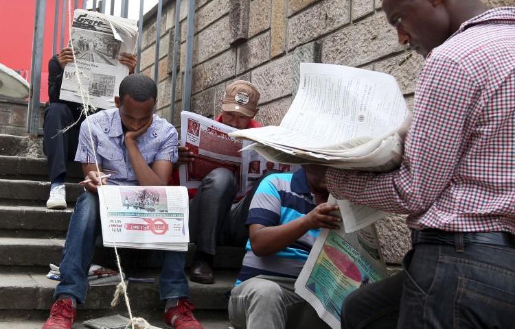 People read newspapers in Ethiopia's capital, Addis Ababa, on May 22, 2015. Two journalists were recently detained and attacked while reporting in Legetafo, a town in Ethiopia's Oromia region. (Tiksa Negeri/Reuters)