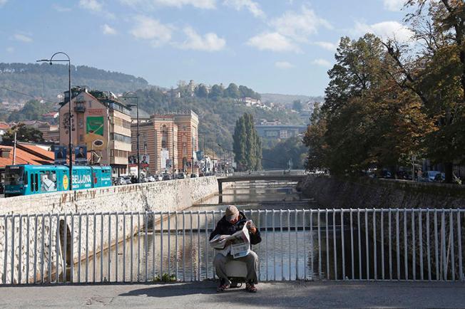 A man reads on a bridge in Sarajevo, Bosnia and Herzegovina, on October 6, 2018. A Sarajevo politician recently attacked a journalist in the city. (Amel Emric/AP)