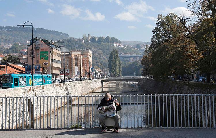 A man reads on a bridge in Sarajevo, Bosnia and Herzegovina, on October 6, 2018. A Sarajevo politician recently attacked a journalist in the city. (Amel Emric/AP)