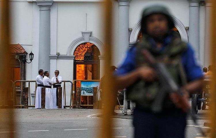 Priests are seen in the background as security personnel stand guard in front of St Anthony's shrine on April 29, 2019, days after a string of suicide bomb attacks across the island on Easter Sunday killed hundreds. (Reuters/Danish Siddiqui)
