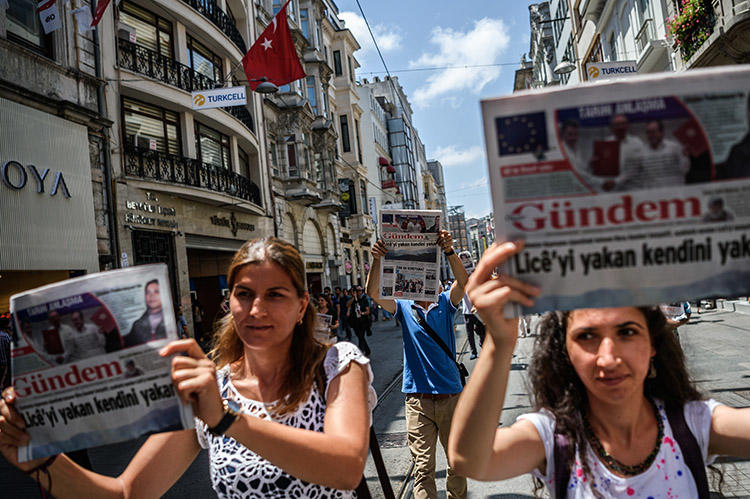 Protesters hold up copies of the pro-Kurdish daily Özgür Gündem during a rally in Istanbul in June 2016. Turkish courts will proceed with 14 cases against a former publisher of the now shuttered newspaper. (AFP/Oan Kose)