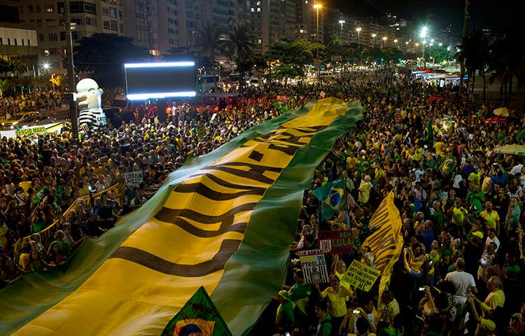 Manifestantes estendem uma faixa nas cores da bandeira brasileira durante um protesto contra o ex-presidente Luiz Inácio Lula da Silva no Rio de Janeiro, Brasil, em 3 de abril de 2018. Um tribunal brasileiro ordenou que a revista on-line Crusoé removesse uma reportagem sobre um juiz. 15 de abril de 2019. (AP Photo/Silvia Izquierdo)