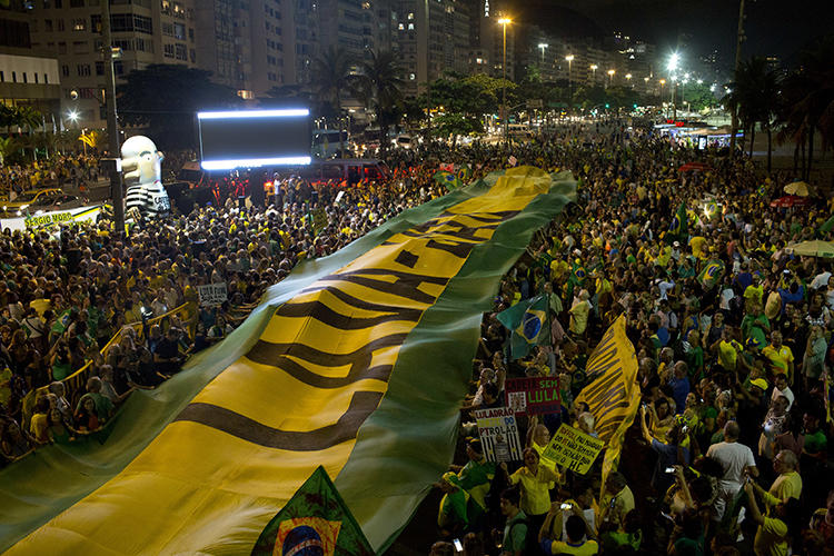 Manifestantes estendem uma faixa nas cores da bandeira brasileira durante um protesto contra o ex-presidente Luiz Inácio Lula da Silva no Rio de Janeiro, Brasil, em 3 de abril de 2018. Um tribunal brasileiro ordenou que a revista on-line Crusoé removesse uma reportagem sobre um juiz. 15 de abril de 2019. (AP Photo/Silvia Izquierdo)