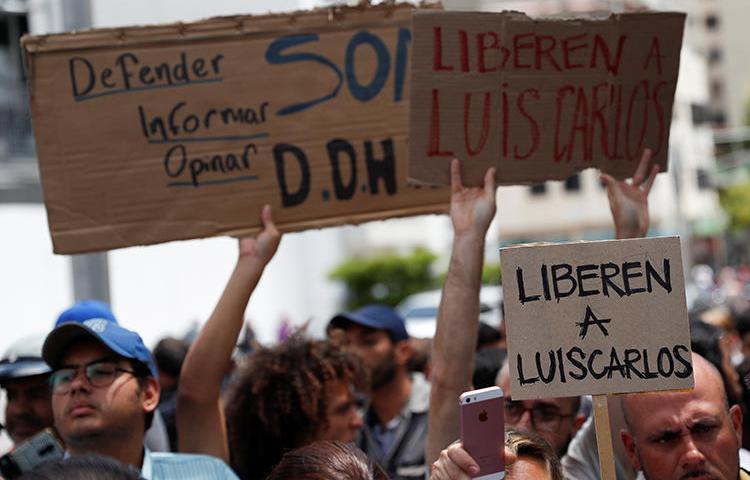 People hold placards reading "Free Luis Carlos" outside the office of Venezuela's attorney general in Caracas on March 12, 2019. The journalist was released later on March 12. (Reuters/Carlos Garcia Rawlins)