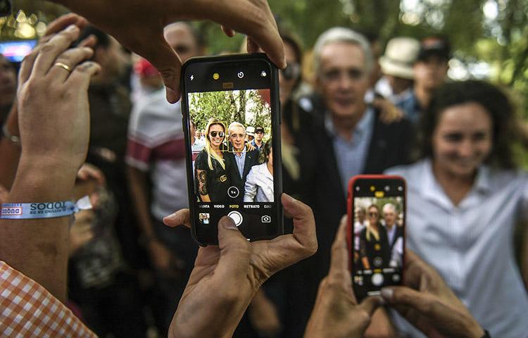 Álvaro Uribe, center, poses for pictures with supporters at his home in Rionegro, Colombia, in June 2018. Colombia's former president filed a civil defamation suit in the U.S. against journalist Daniel Coronell. (AFP/Joaquin Sarmiento)