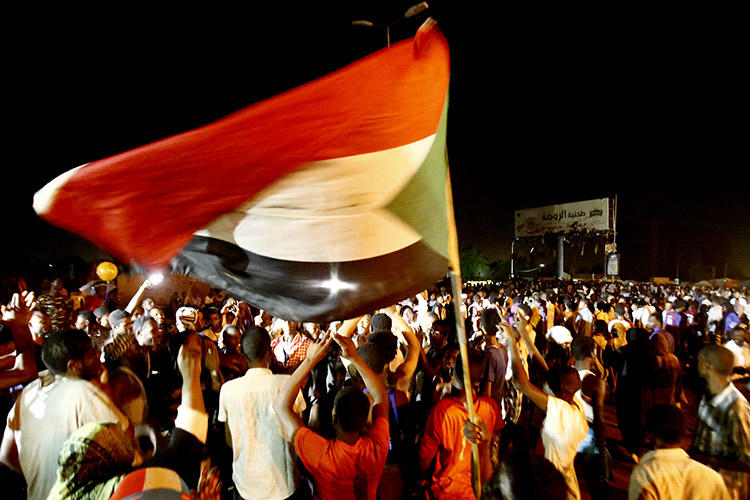 Sudanese wave flags and chant slogans as they gather outside the army headquarters in Khartoum on May 30. Sudan's military rulers have ordered Al-Jazeera's Khartoum bureau to be shut down. (AFP/Ashraf Shazly)