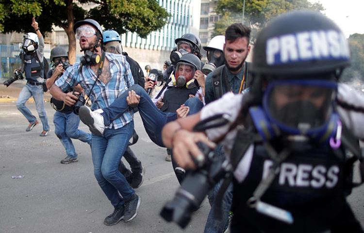 Un trabajador de la prensa herido es cargado durante una protesta contra el gobierno del Presidente Nicolás Maduro y para conmemorar el día del trabajador en Caracas, Venezuela, el 1ero de mayo, de 2019. (Reuters/Ueslei Marcelino)