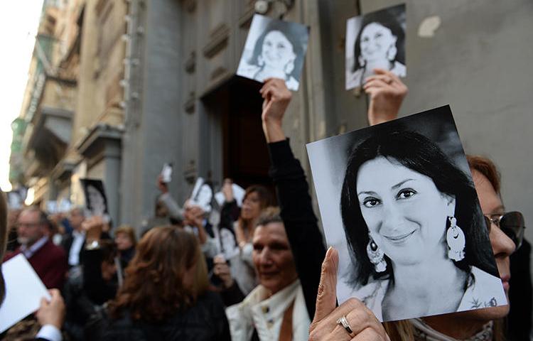 People are seen holding photos of journalist Daphne Caruana Galizia in Valletta, Malta, on April 16, 2018. The Parliamentary Assembly of the Council of Europe recently passed a resolution requiring the Maltese government to launch an independent public inquiry into her killing. (AFP/Matthew Mirabelli)