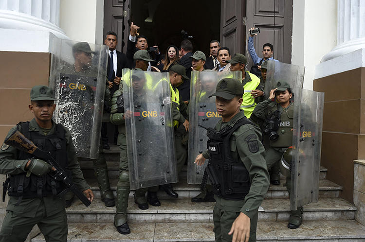 Miembros de la Guardia Nacional Bolivariana impiden a los periodistas entrar a la Asamblea Nacional, en Caracas, Venezuela, el 18 de junio de 2019. Los oficiales han bloqueado la entrada de los periodistas al edificio de la Asamblea durante los debates celebrados los días martes, desde el 7 de mayo. (AFP/Yuri Cortez)