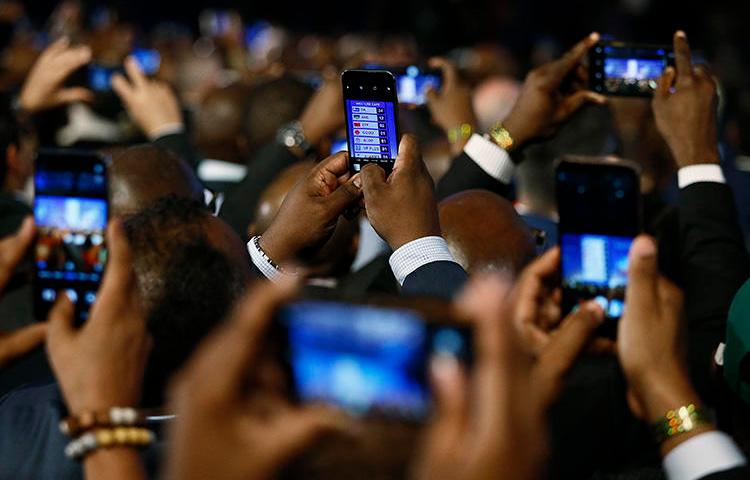 People take pictures with cells phones during the formal announcement of election results in Pretoria on May 11. Journalists covering the election had to contend with online harassment, doxxing, and threats. (AFP/Phill Magakoe)