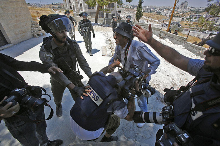 A picture taken in Dar Salah on August 2 shows Israeli border police scuffling with a journalist. At least 3 journalists were injured covering protests in Gaza and the West Bank on August 2. (AFP/Musa Al-Shaer)