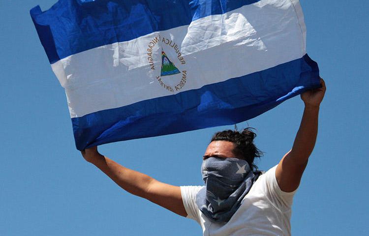 AUn manifestante despliega una bandera de Nicaragua en Managua, el 16 de marzo de 2019.  Periodistas que cubrían protestas antigubernamentales a lo largo del país fueron atacados, acosados y, en algunos casos, detenidos. (AFP/Maynor Valenzuela)