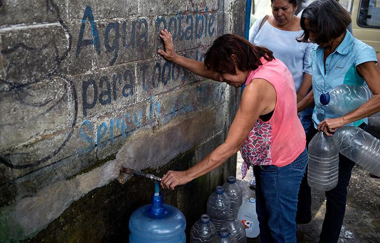 Una mujer llena un bidón de agua en una estación en San Juán de los Morros, Estado Guárico, Venezuela, el 10 de julio de 2018. El 18 de julio de 2019 un periodista fue detenido en San Juán de los Morros bajo la ‘ley del odio’ venezolana por criticar a un político regional. (AFP/Federico Parra)