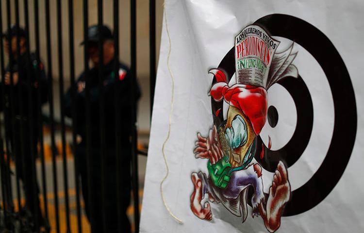 A banner featuring a cartoon of an injured journalist and a headline in Spanish reading, 'We want journalists alive. Not one more,' hangs outside the Secretary of the Interior building in Mexico City on August 21. A reporter was stabbed to death in the state of Estado de México on August 24. (AP/Rebecca Blackwell)