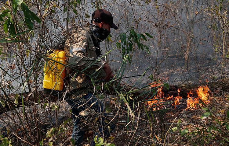 Un voluntario se esfuerza por apagar un incendio forestal en Quitunuquina, en las afueras de Robore, Bolivia, el 24 de agosto de 2019. Los incendios forestales de Bolivia han puesto al descubierto los numerosos riesgos que enfrentan los periodistas ambientales. (AP Photo/Juan Karita)