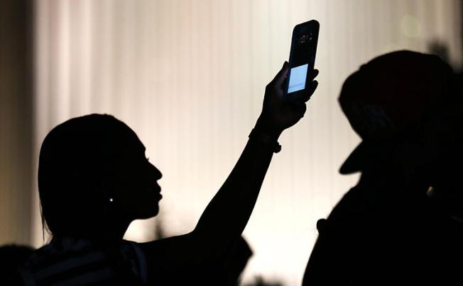 A protester uses her phone to film during protests in Charlotte, North Carolina, in September 2016. CPJ's safety survey found 85 percent of respondents believe journalism is becoming a less safe job. (Reuters/Mike Blake)