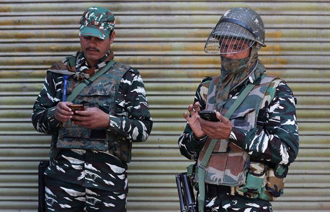 Indian paramilitary soldiers use their cellphones in Srinagar, Indian controlled Kashmir, on October 14, 2019 after the partial lifting of a communications lockdown in place since India's government downgraded the region's semi-autonomy in August. (AP Photo/Mukhtar Khan)