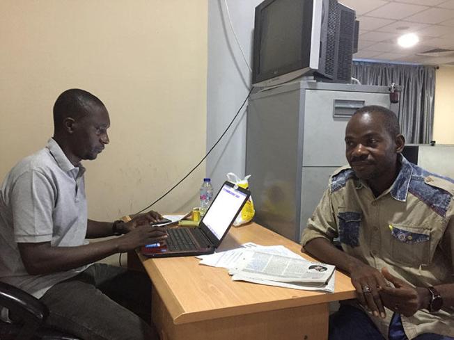 Hamza Idris (left), an editor with the Daily Trust newspaper, sits with colleague Hussaini Garba Mohammed in their office in the Nigerian capital, Abuja, in February 2019. The office was raided in January by the military, who seized 24 computers. (CPJ/Jonathan Rozen)