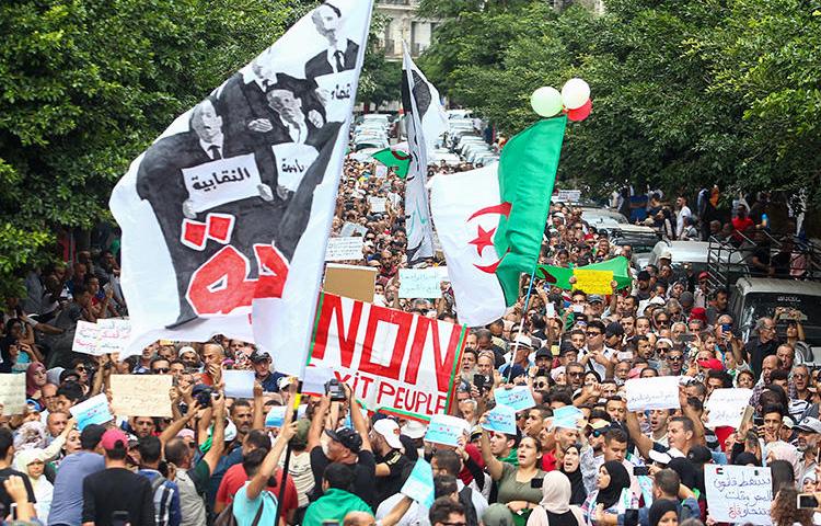 Algerian demonstrators chant and wave their country's national flag as they take part in an anti-government protest in the capital Algiers on October 15, 2019. Authorities have detained at least three more journalists in recent days. (AFP)