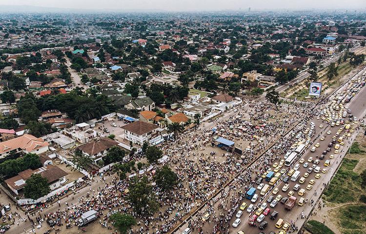 Vue aérienne de la foule rassemblée à l’extérieur du siège de l’Union pour la démocratie et le progrès social  (UDPS) à Kinshasa le 30 mai 2019, alors que les partisans attendent le retour des dépouilles de l’ancien premier ministre congolais et du leader de l’opposition Etienne Tshisekedi, morts en Belgique en  2017. Un journaliste radio congolais a été attaqué par des partisans de l’UDPS lors d’un rallye à Kinshasa le 5 octobre  2019. (AFP/Alexis Huguet)