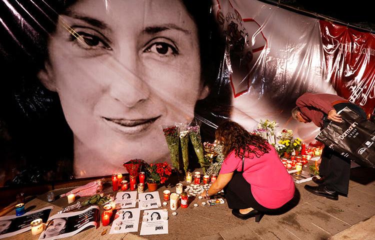 People lay flowers and candles at a memorial during a vigil and protest on the first anniversary of the assassination of journalist Daphne Caruana Galizia outside the Courts of Justice in Valletta, Malta, on October 16, 2018. On the second anniversary of her murder, CPJ joined a call to end impunity in her case. (Reuters/Darrin Zammit Lupi)