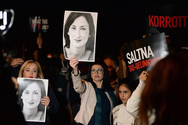 Protesters hold up placards and pictures of the murdered Maltese blogger Daphne Caruana Galizia as they gather outside the prime minister's office in Valletta, Malta, on November 20, 2019. CPJ and other press freedom groups are reiterating their call for an independent investigation into the journalist's killing. (AFP/Matthew Mirabelli)