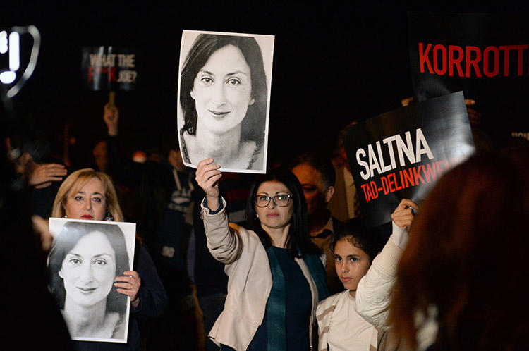 Protesters hold up placards and pictures of the murdered Maltese blogger Daphne Caruana Galizia as they gather outside the prime minister's office in Valletta, Malta, on November 20, 2019. CPJ and other press freedom groups are reiterating their call for an independent investigation into the journalist's killing. (AFP/Matthew Mirabelli)