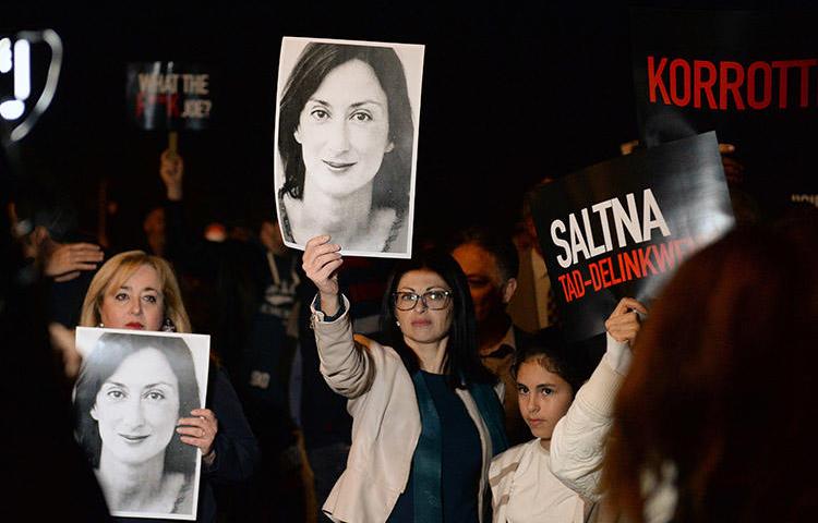 Protesters hold up placards and pictures of the murdered Maltese blogger Daphne Caruana Galizia as they gather outside the prime minister's office in Valletta, Malta, on November 20, 2019. CPJ and other press freedom groups are reiterating their call for an independent investigation into the journalist's killing. (AFP/Matthew Mirabelli)
